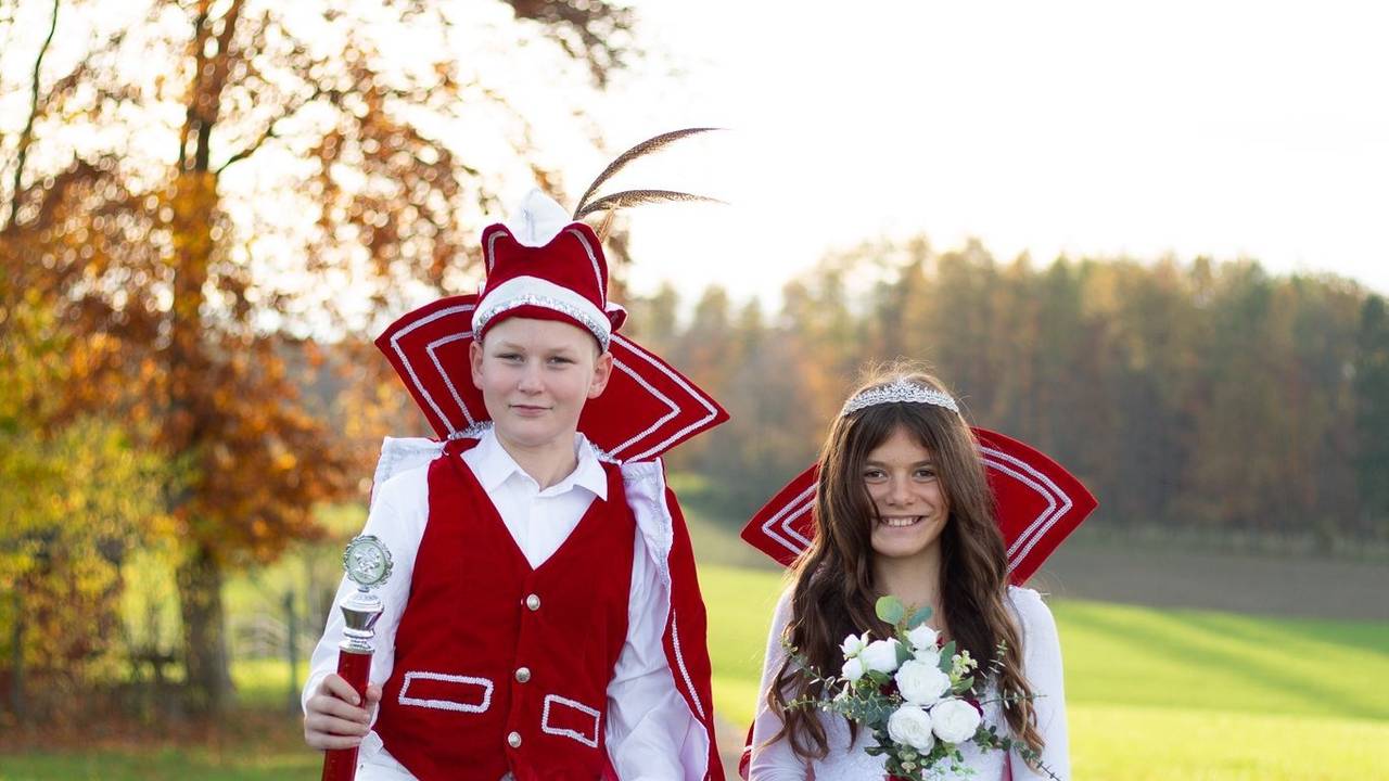 Emmi und Anton stehen im Ornat auf einem Weg, Anton hüpft in die Höhe.