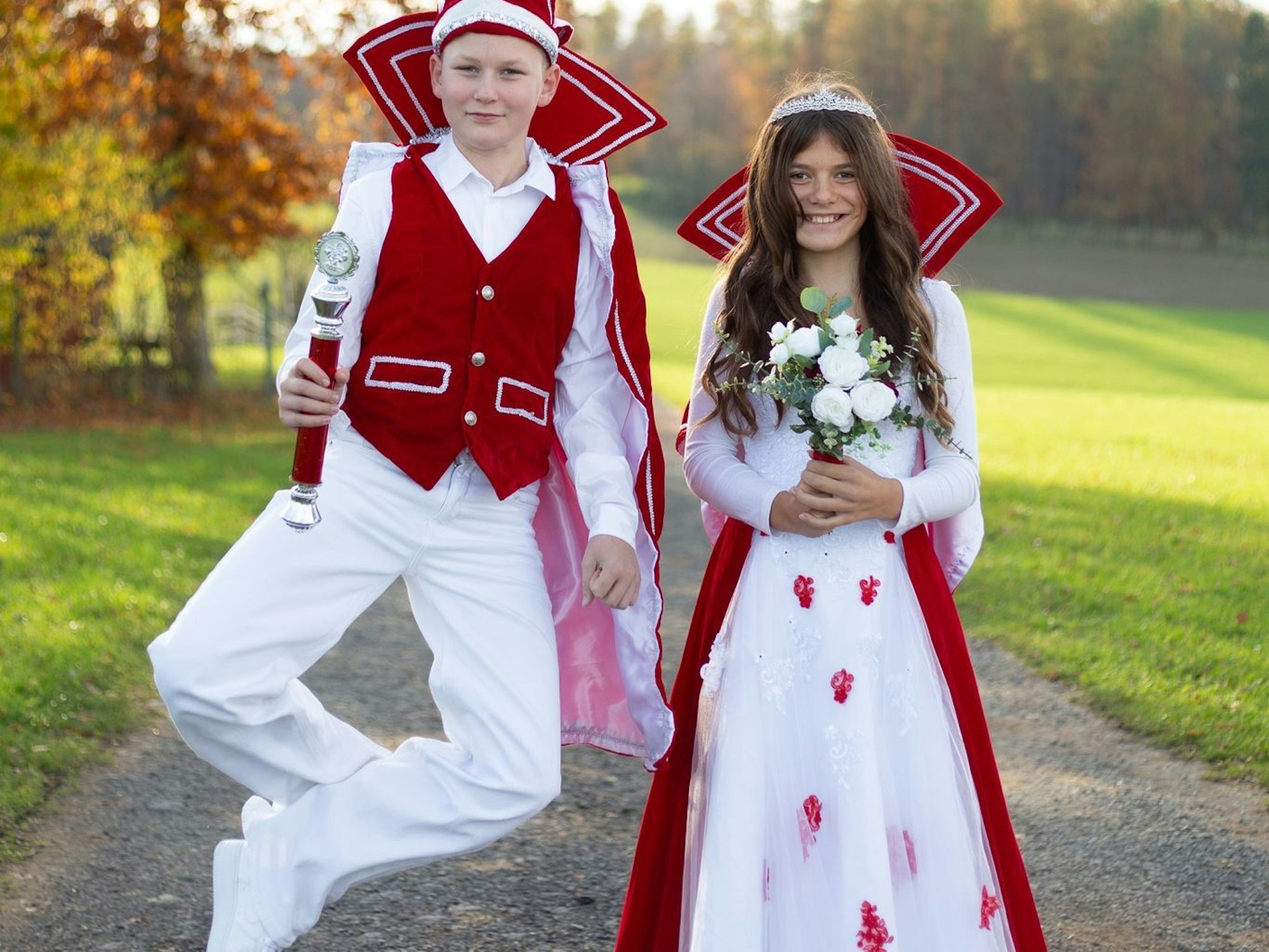 Emmi und Anton stehen im Ornat auf einem Weg, Anton hüpft in die Höhe.