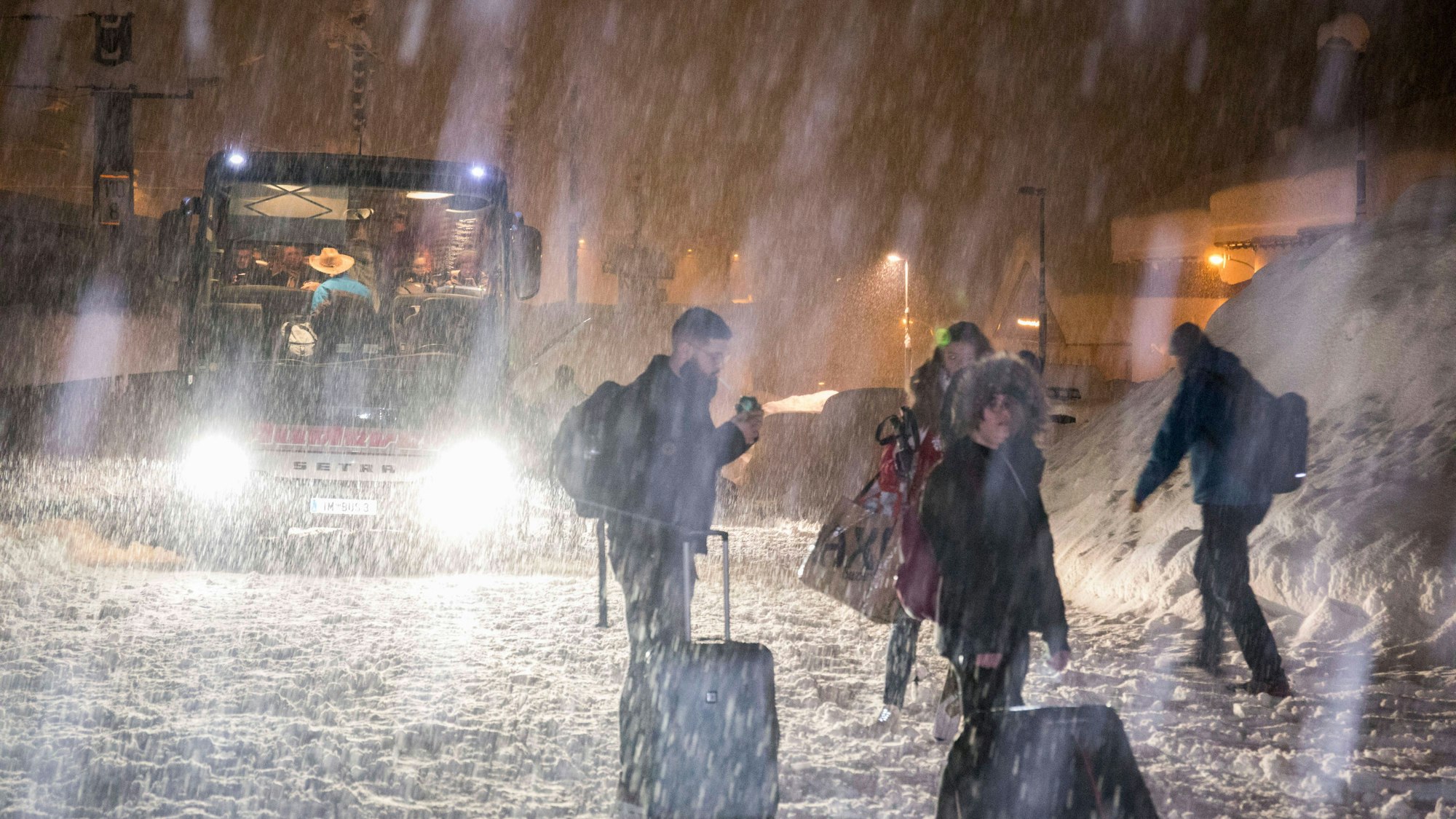 Menschen steigen im starken Schneefall aus einem Bus in einer verschneiten Landschaft