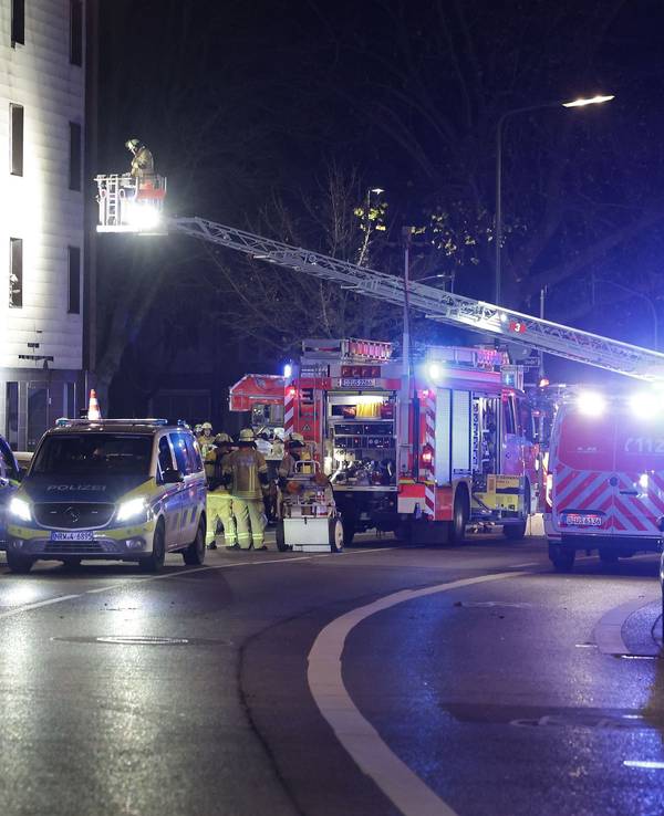 Rettungskräfte arbeiten an einer Fassade eines Mehrfamilienhauses, die nach einer Explosion beschädigt wurde.