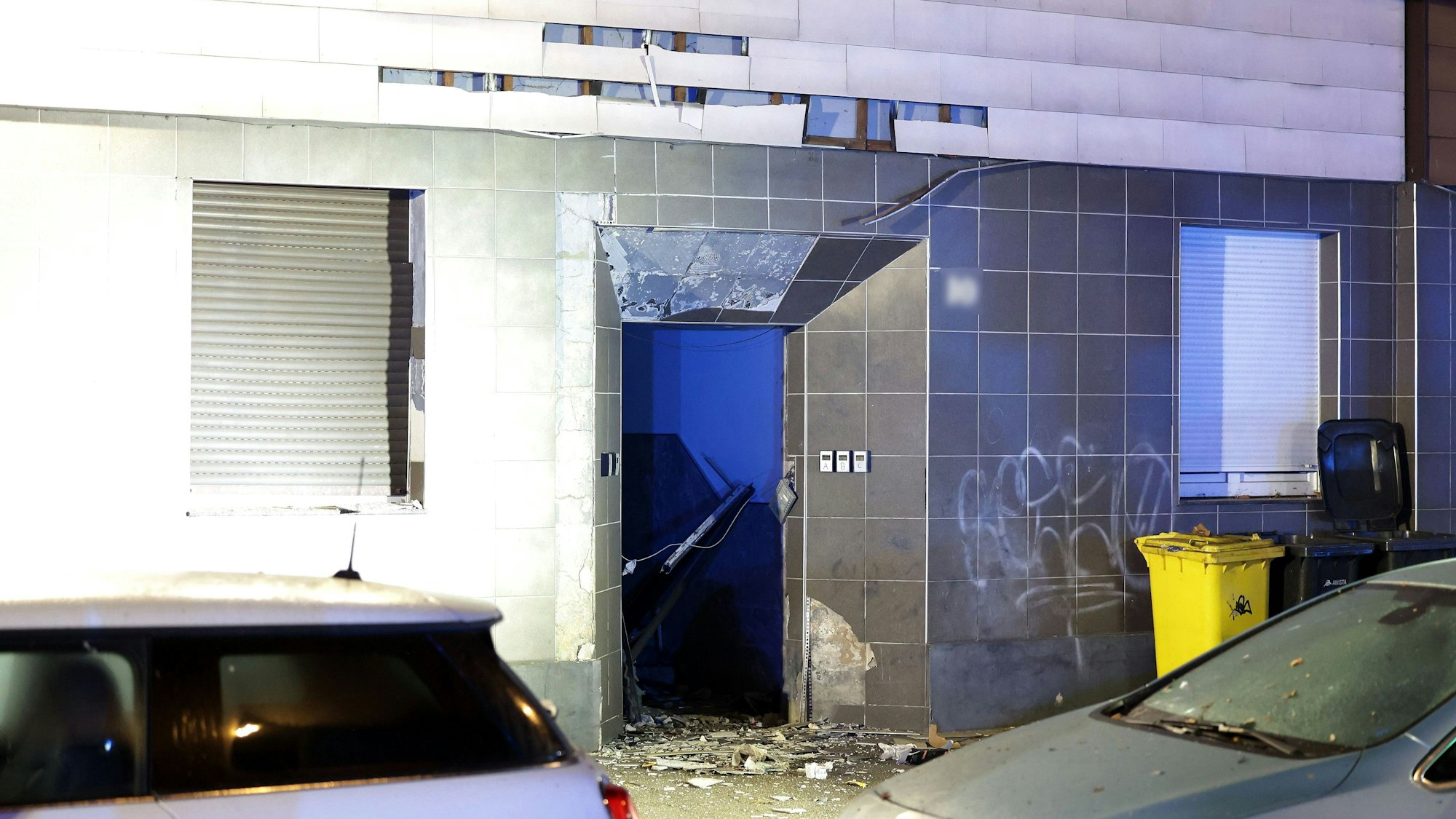 Schutt liegt nach einer Explosion vor dem Eingangsbereich eines Mehrfamilienhauses.
