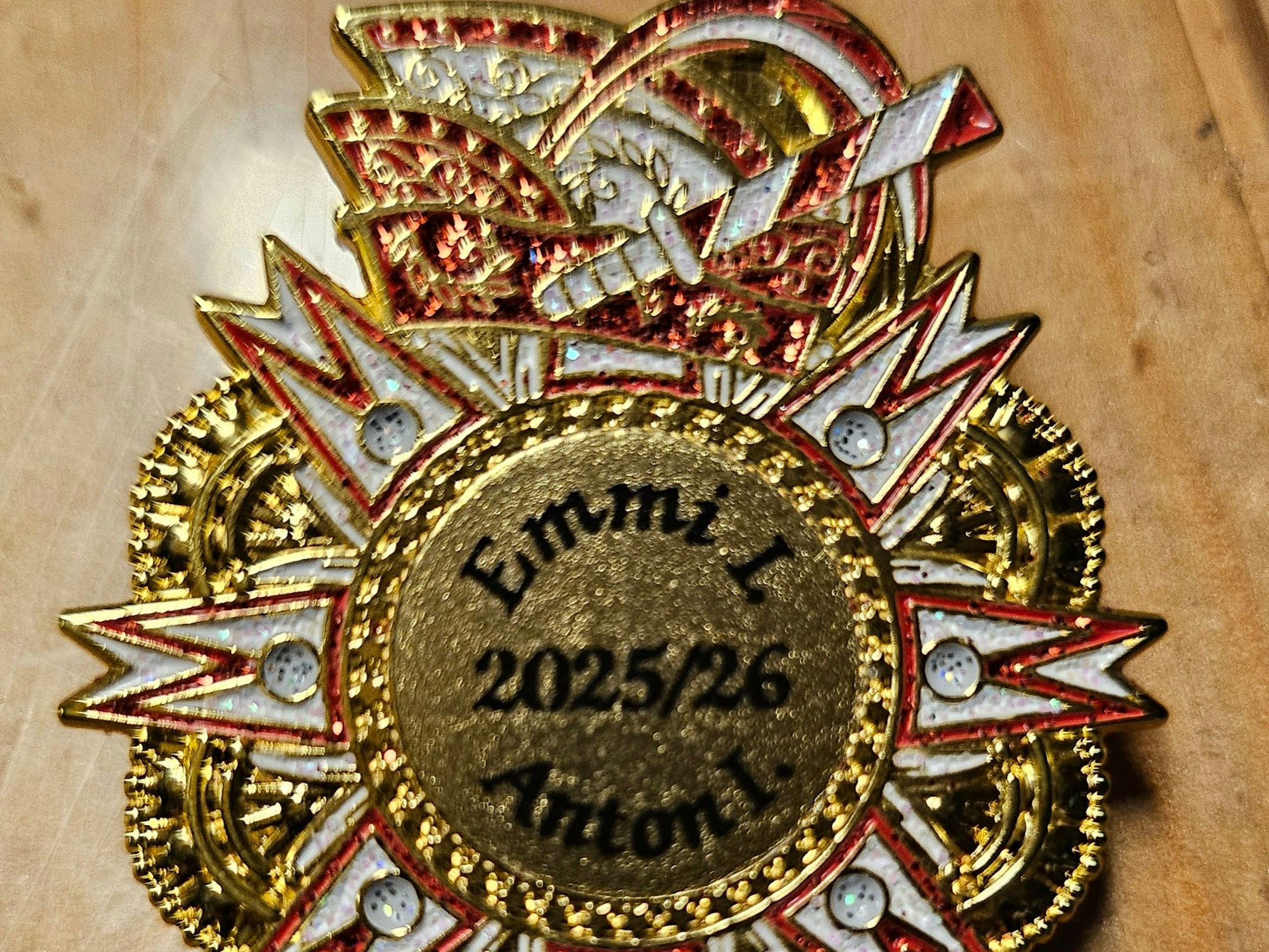 Eine Anstecknadel mit einer Narrenkappe trägt in der Mitte die Namen Emmi und Anton.