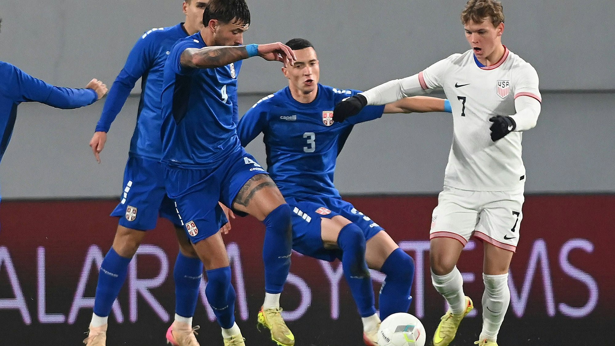 Fußballmatch: Cole Campbell (USA) kämpft mit serbischen Spielern um den Ball