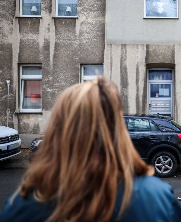 Eine Frau steht vor einem Mehrfamilienhaus. In einem Mehrfamilienhaus in Bochum ist ein zwölfjähriges Mädchen bei einem Polizeieinsatz durch Schüsse aus einer Dienstwaffe lebensgefährlich verletzt worden.