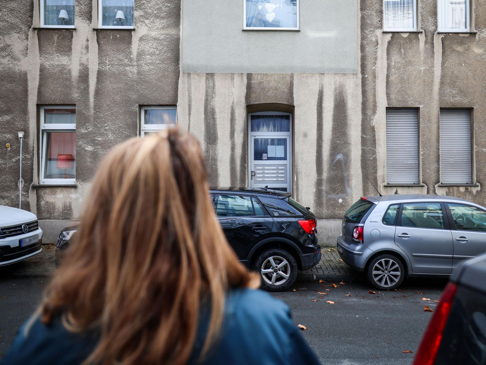 Eine Frau steht vor einem Mehrfamilienhaus. In einem Mehrfamilienhaus in Bochum ist ein zwölfjähriges Mädchen bei einem Polizeieinsatz durch Schüsse aus einer Dienstwaffe lebensgefährlich verletzt worden.