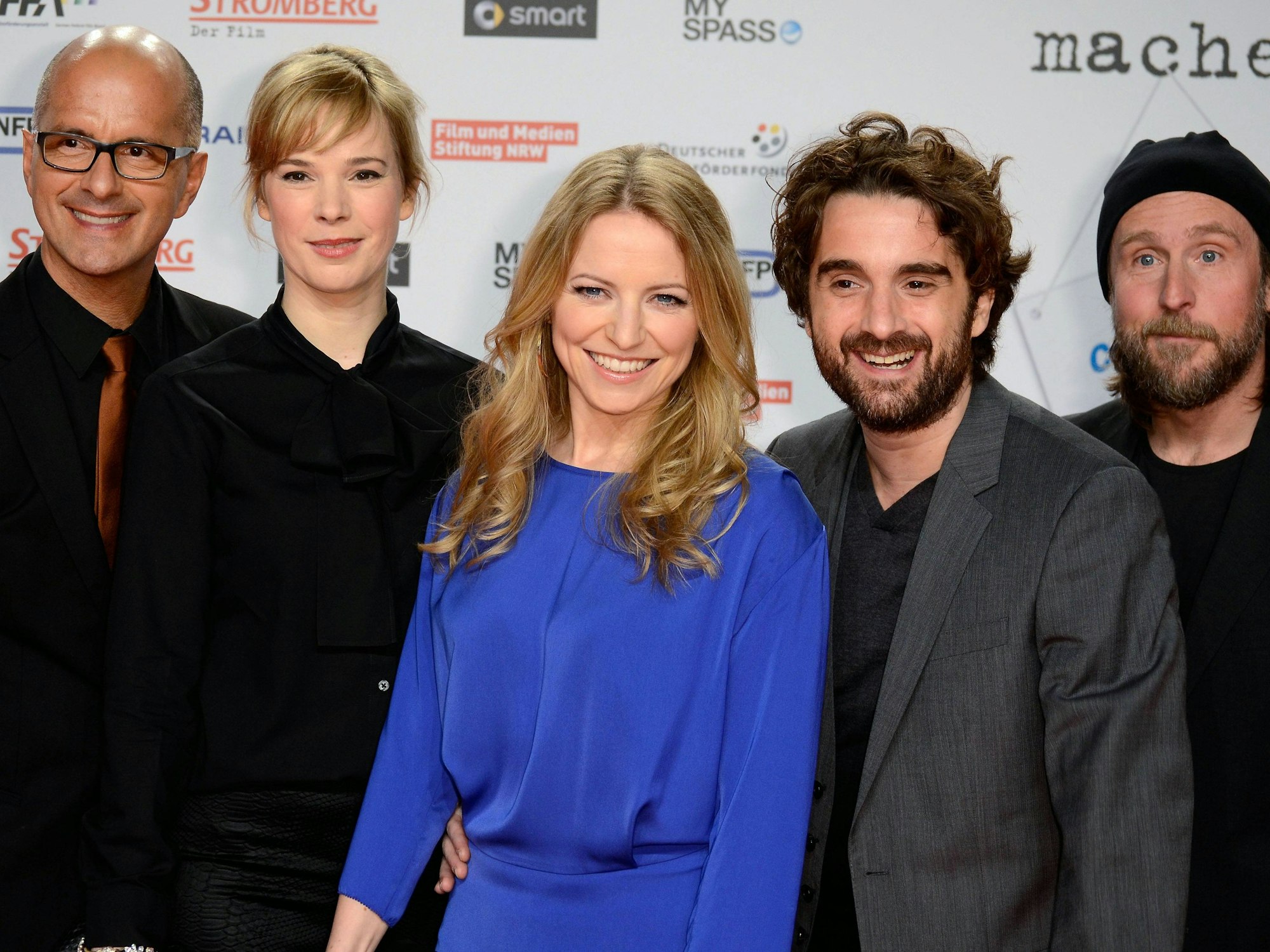 Fünf Schauspielerinnen und Schauspieler lachen in die Kamera.