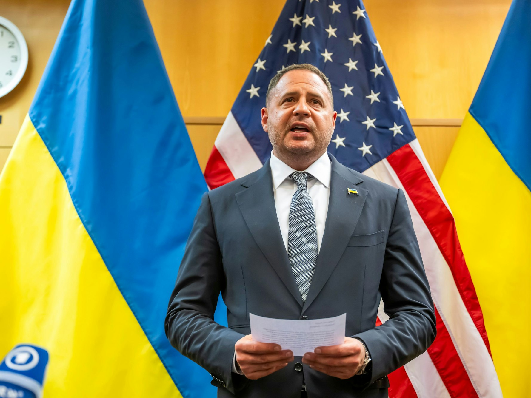 Andrij Jermak, Leiter des Präsidialamts der Ukraine, steht mit einem Zettel in der Hand vor der amerikanischen sowie ukrainischen Flagge.