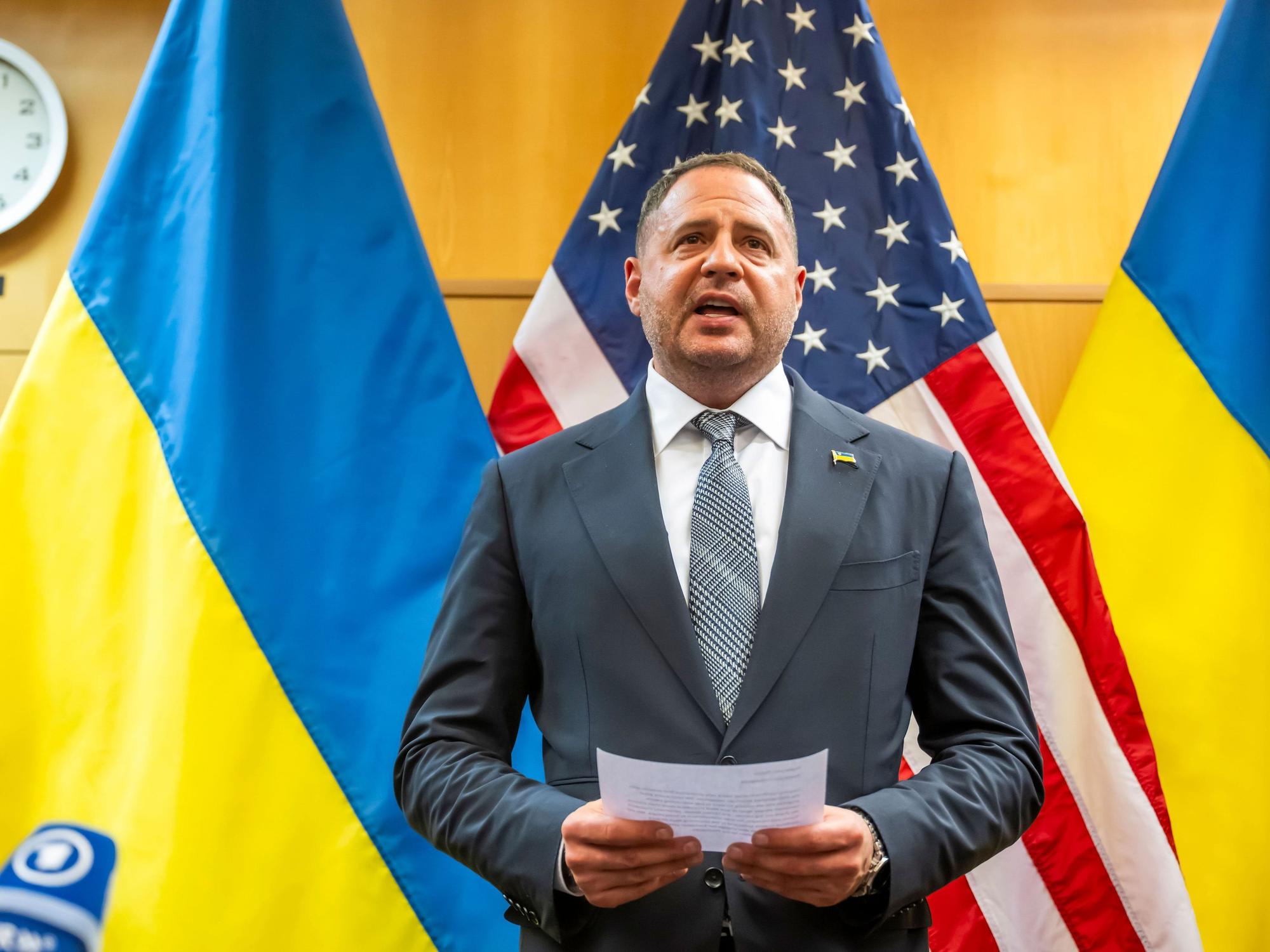 Andrij Jermak, Leiter des Präsidialamts der Ukraine, steht mit einem Zettel in der Hand vor der amerikanischen sowie ukrainischen Flagge.