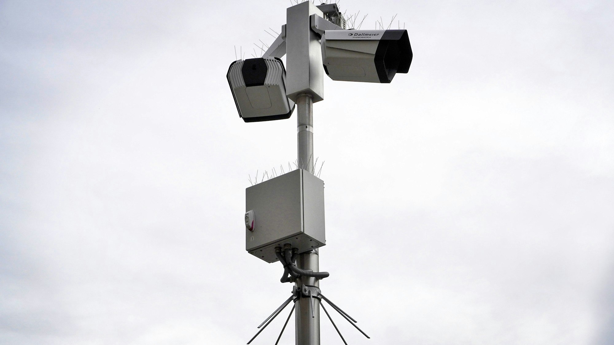 Zwei Dallmeier PANOMERA Überwachungskameras auf einem Mast mit Spikes vor hellem Himmel