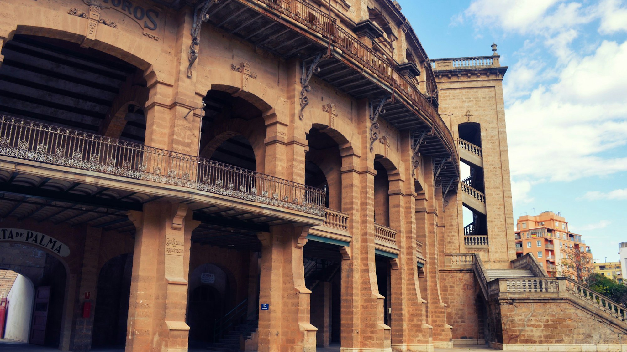Außenansicht der Plaza de Toros Palma, ein großes Steinbauwerk mit Bögen und Balkonen unter blauem Himmel