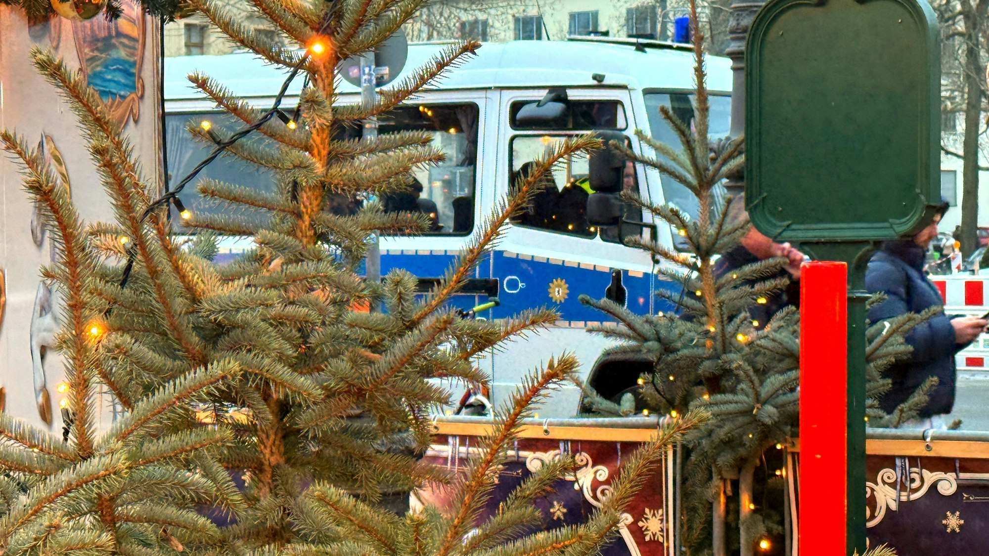 Weihnachtsdekoration mit Lichtern, dahinter ein teilweise sichtbarer Polizeiwagen am Berliner Weihnachtsmarkt