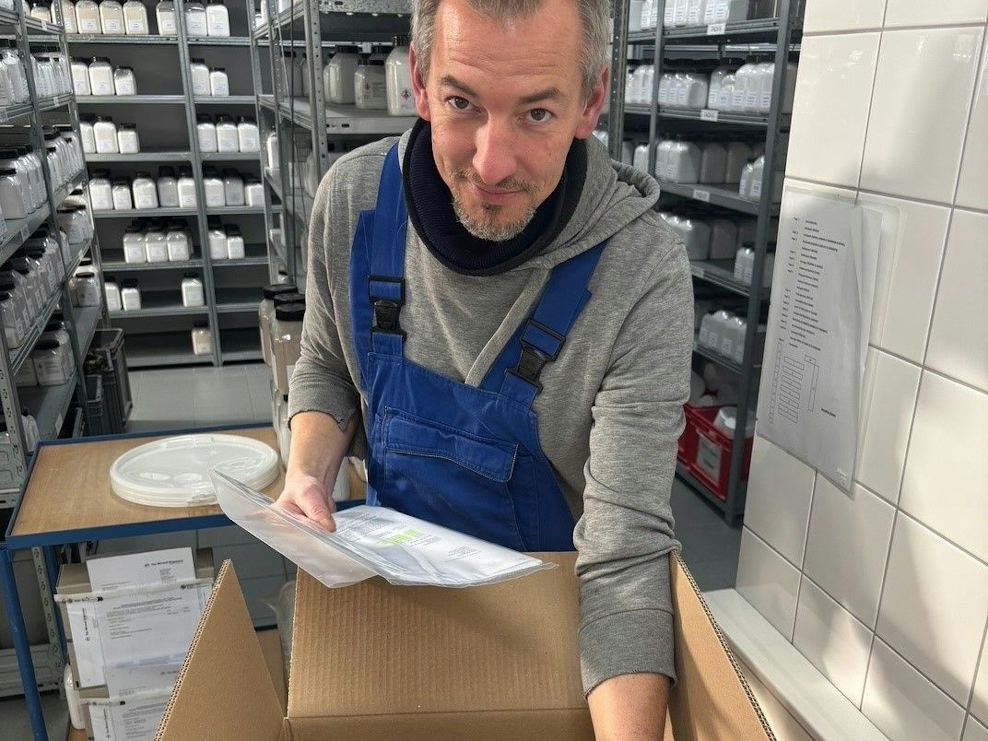 Auf dem Bild ist ein Mann zu sehen, der die Produktproben in einen Karton packt.