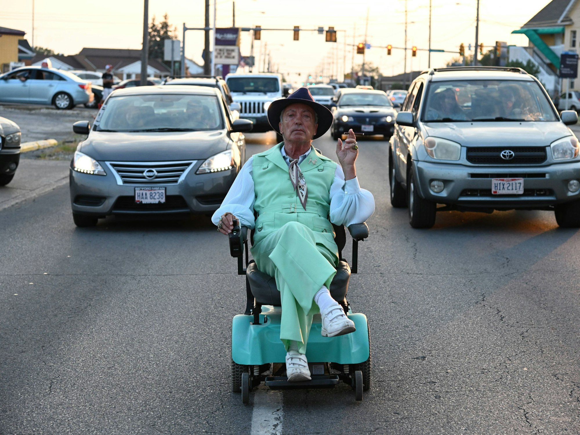 Ein Mann fährt in einem kleinen Elektromobil vor Autos her.