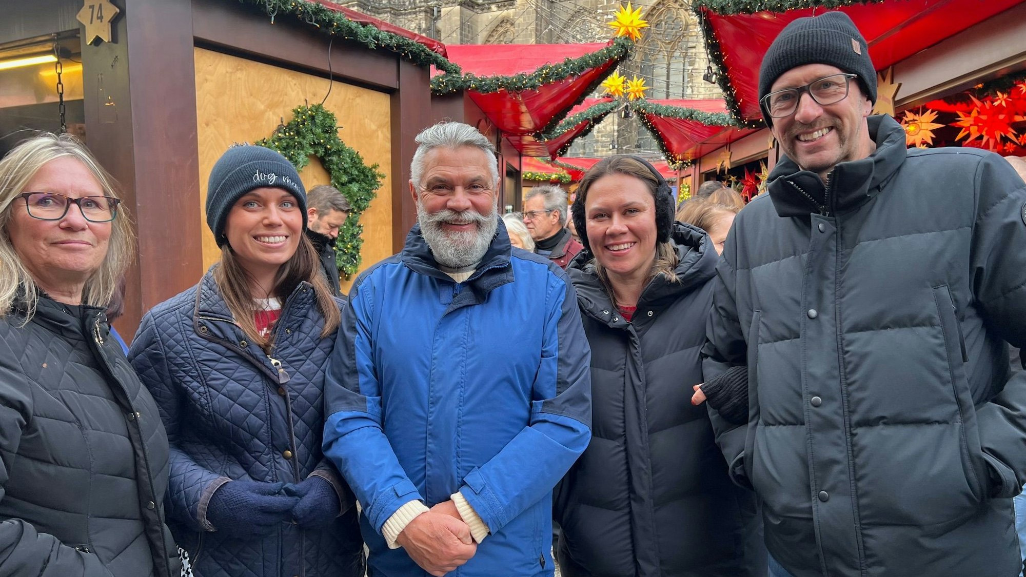Eine Familie aus England posiert lächelnd auf dem Weihnachtsmarkt am Kölner Dom.