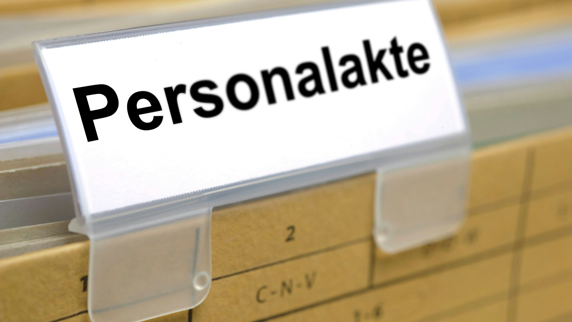 Nahaufnahme eines Aktenreiters mit der Aufschrift 'Personalakte' in einem Aktenregal