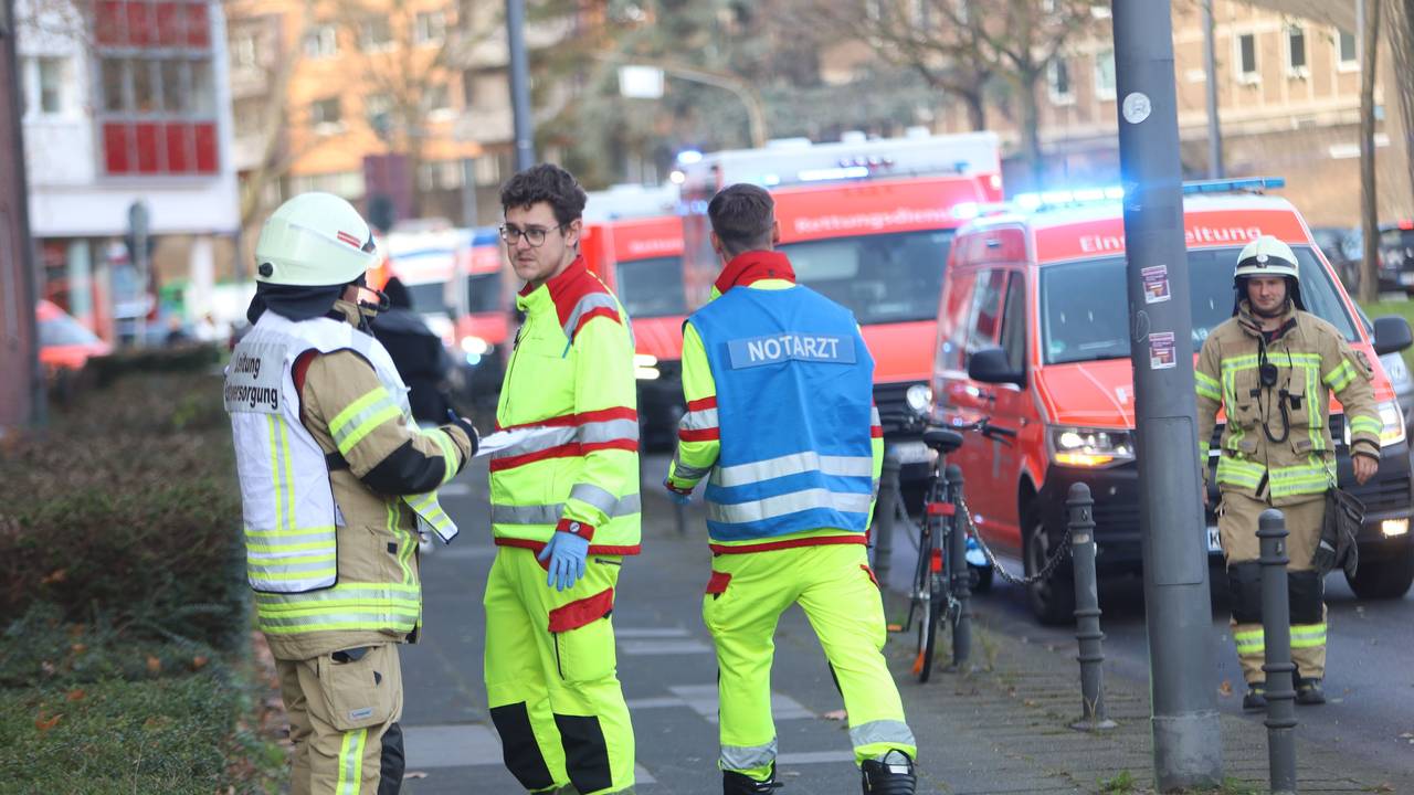 Einsatzkräfte, darunter ein Notarzt, sind im Einsatz. An der Straße stehen mehrere Einsatzfahrzeuge von Feuerwehr und Rettungsdiens.t