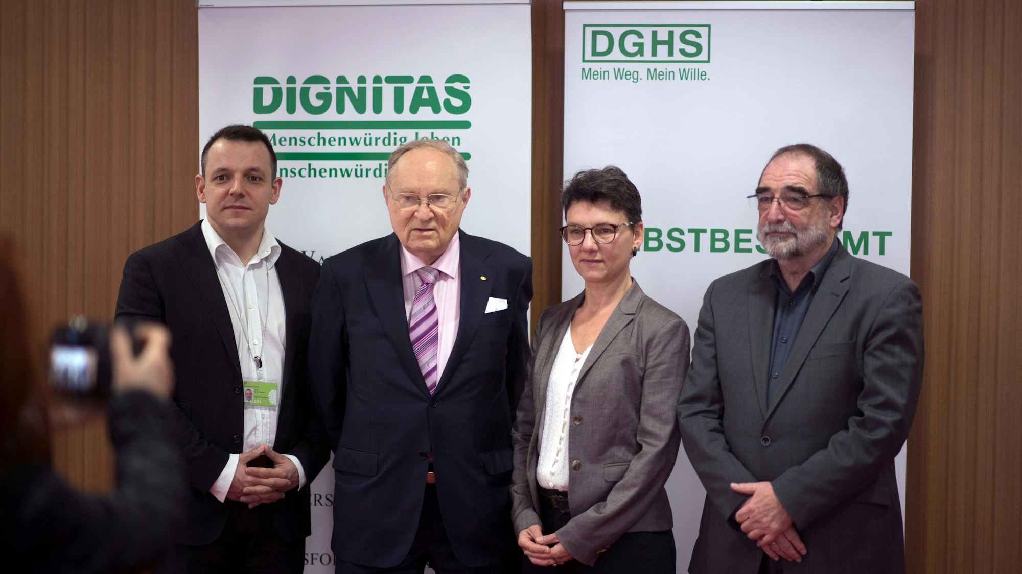 Vier Personen, darunter Ludwig Minelli, stehen vor Bannern von Dignitas und DGHS