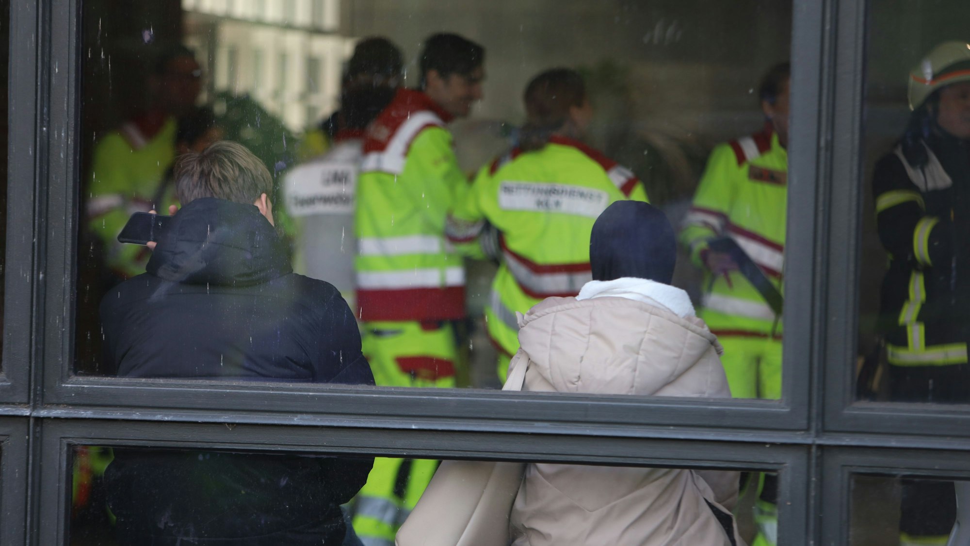 Einsatzkräfte sind in einem Gebäude, am Fenster sitzen zwei junge Menschen.