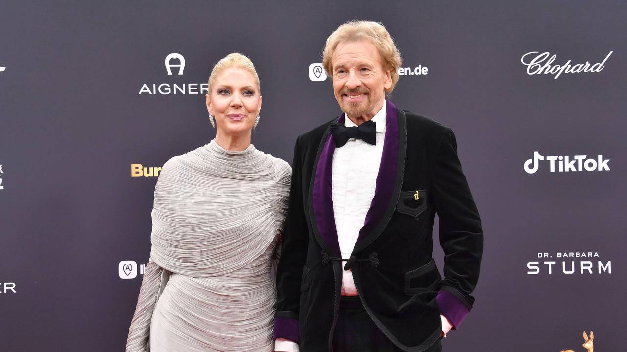 Thomas Gottschalk und Karina Mroß lächeln, Händchen haltend auf dem roten Teppich