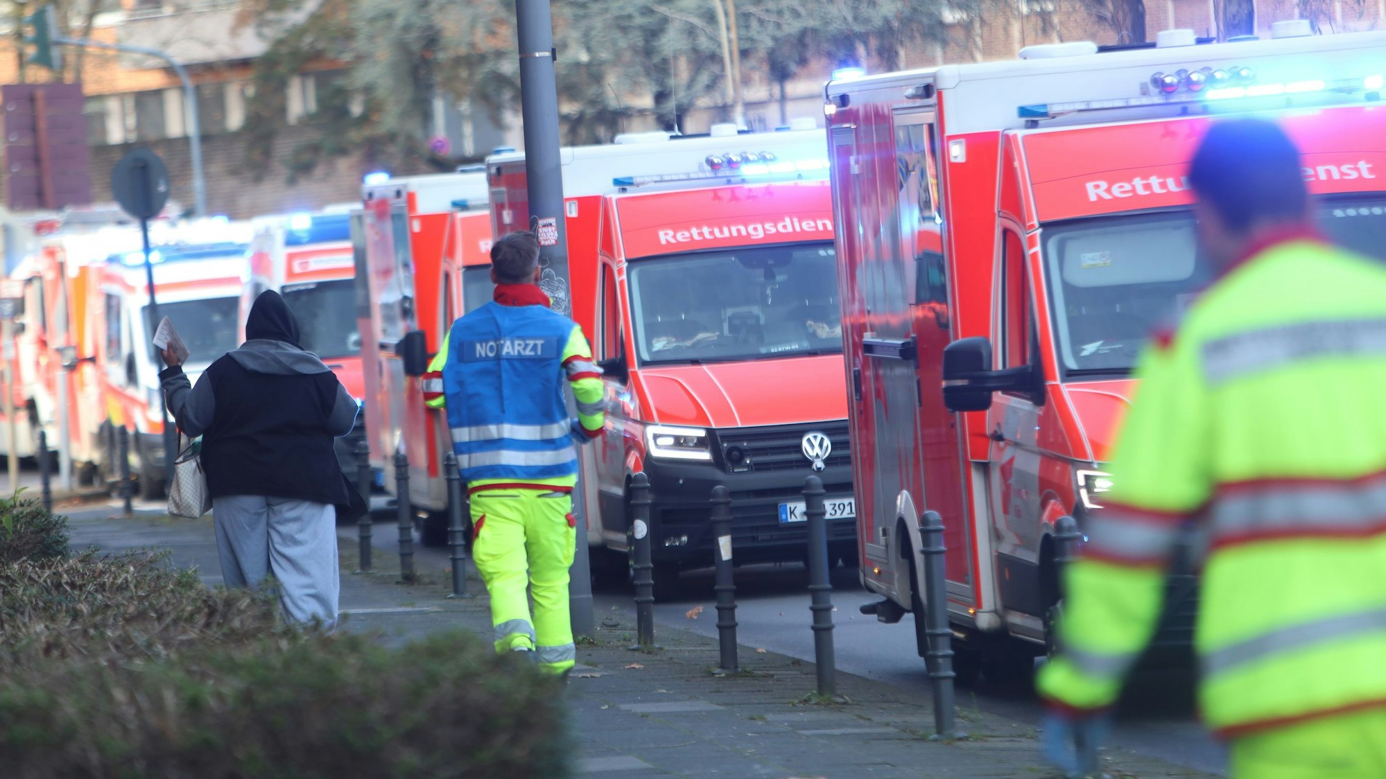 Einsatzfahrzeuge des Rettungsdienstes säumen eine Straße, ein Notarzt rennt zu einem Fahrzeug.