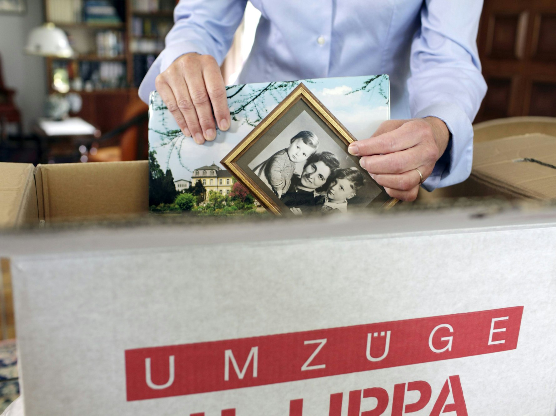 Eine Seniorin packt einen Umzugskarton.