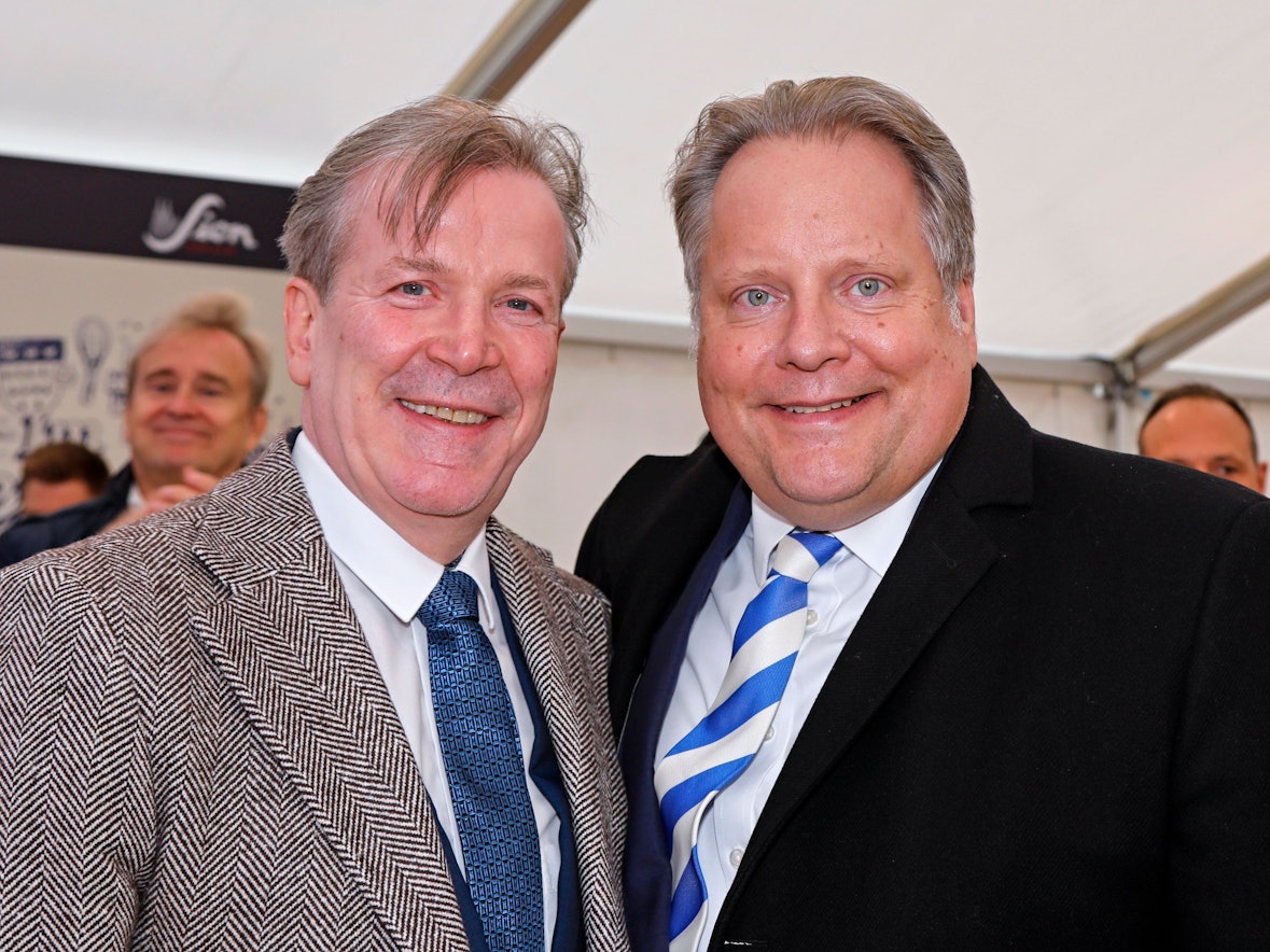 Zwei Männer grinsen in die Kamera.