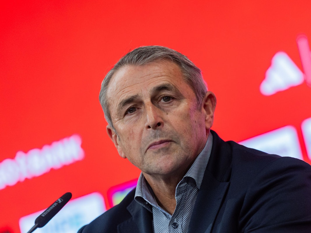 Klaus Allofs sitzt bei einer Pressekonferenz vor einem Mikrofon.