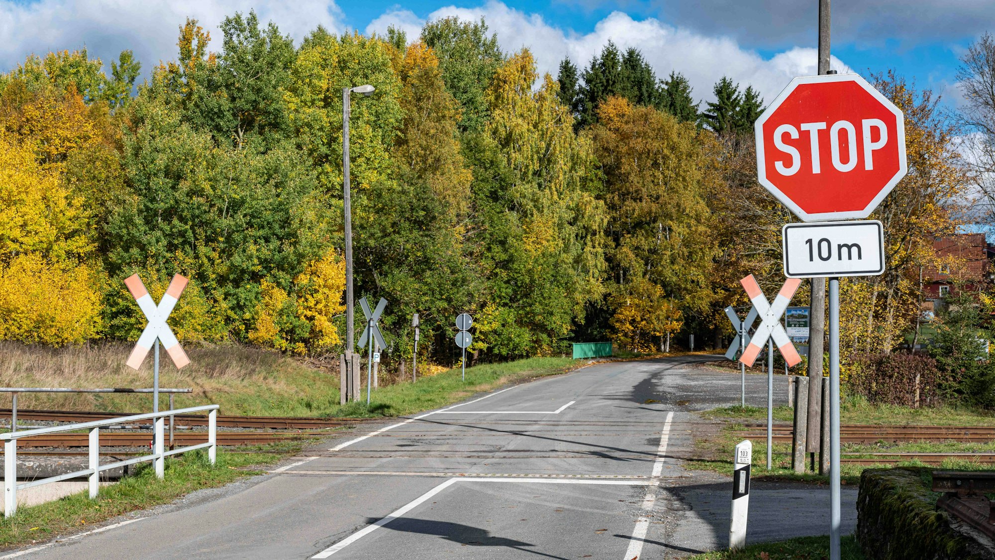 Unbeschrankter Bahnübergang mit Stoppschild und Andreaskreuzen im Herbst