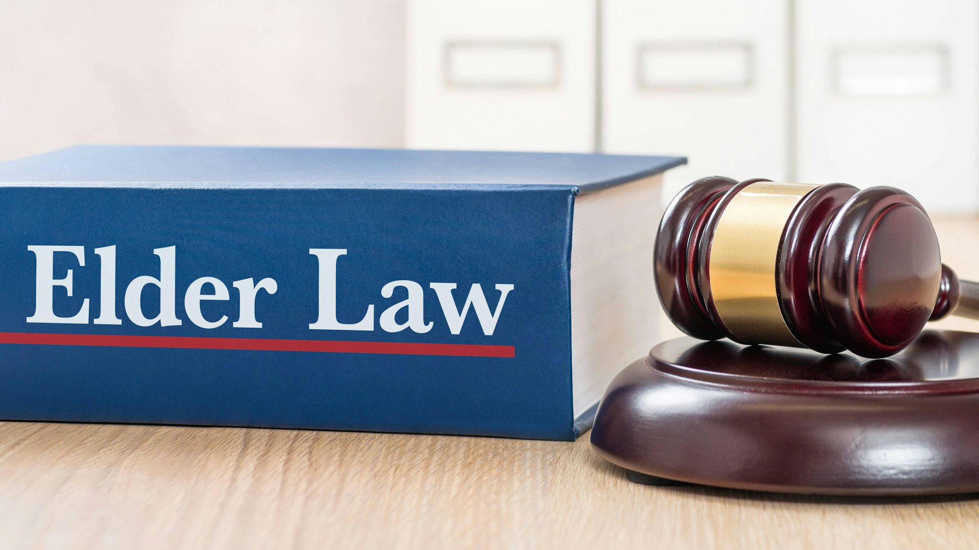 Ein blauer Gesetzesband 'Elder Law' und ein Richthammer auf einem Holztisch