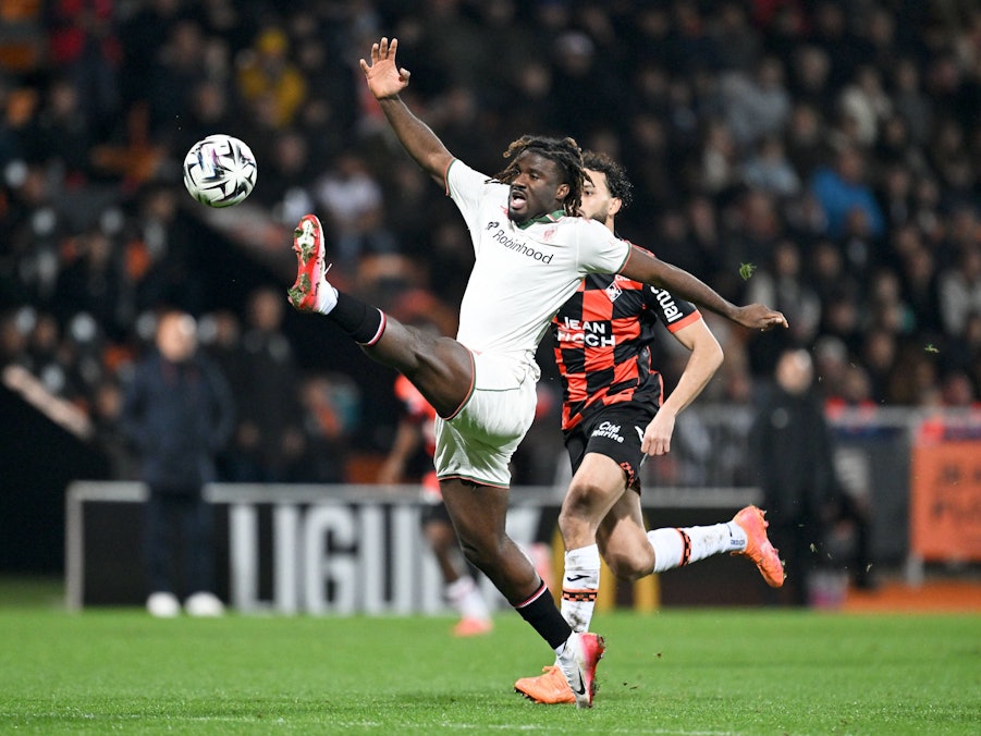 Terem Moffi im weißen Trikot tritt einen Fußball auf dem Spielfeld