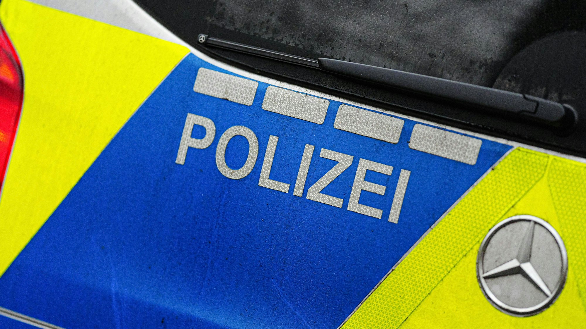 Nahaufnahme eines Mercedes-Benz Polizeiwagens mit "POLIZEI"-Schriftzug und blauen sowie gelben Reflexstreifen