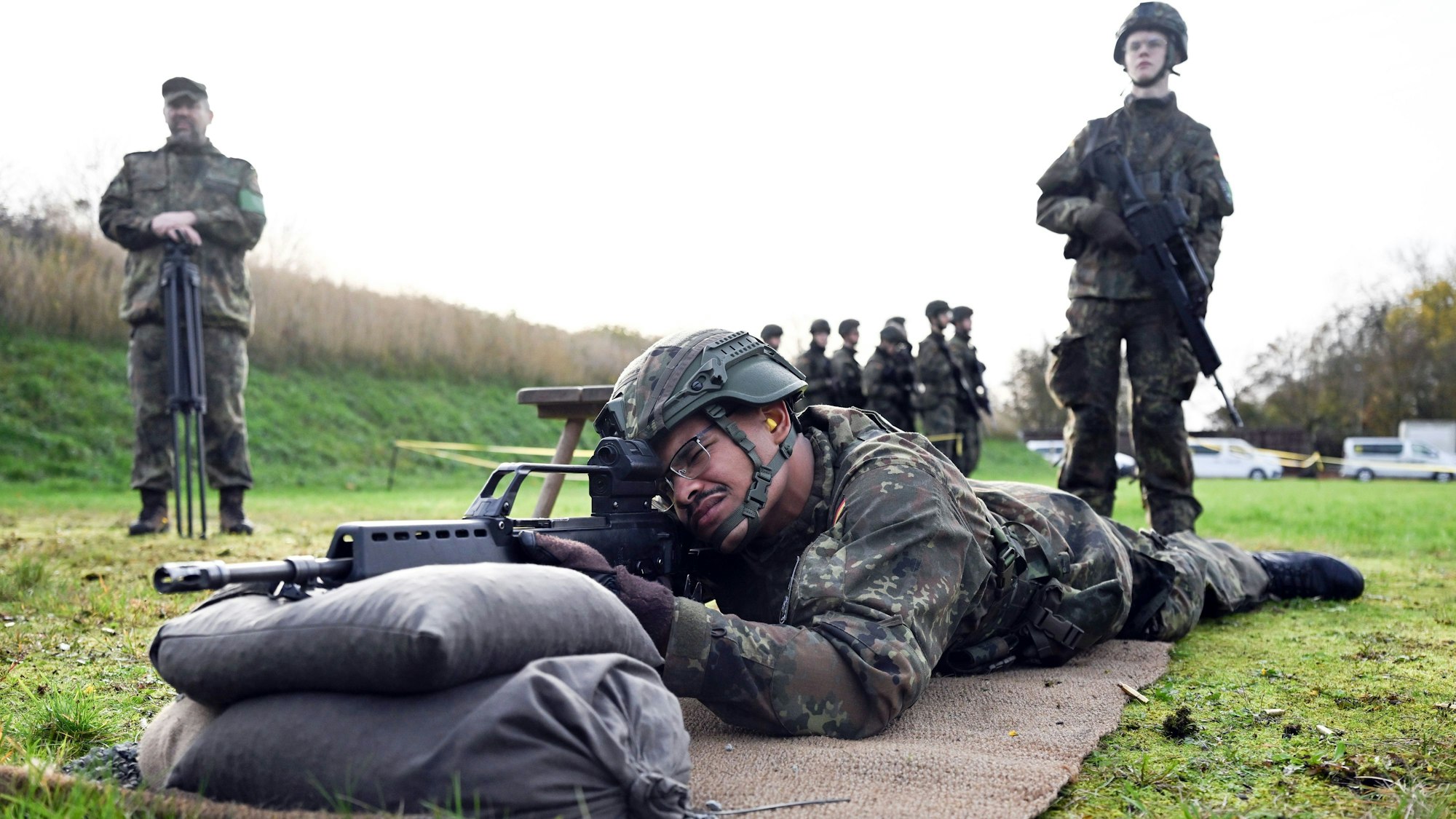 Ein Soldat liegt auf dem Boden, das Gewehr auf Sandsäcken vor sich.