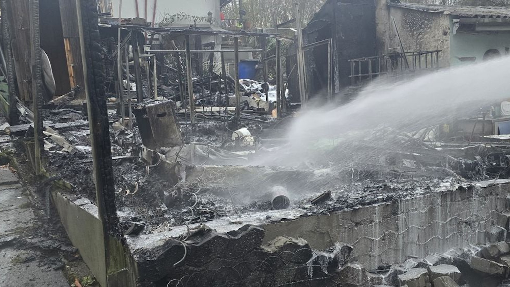 Gartenlaube in Kleingartenanlage brennt, Feuerwehr im Einsatz.