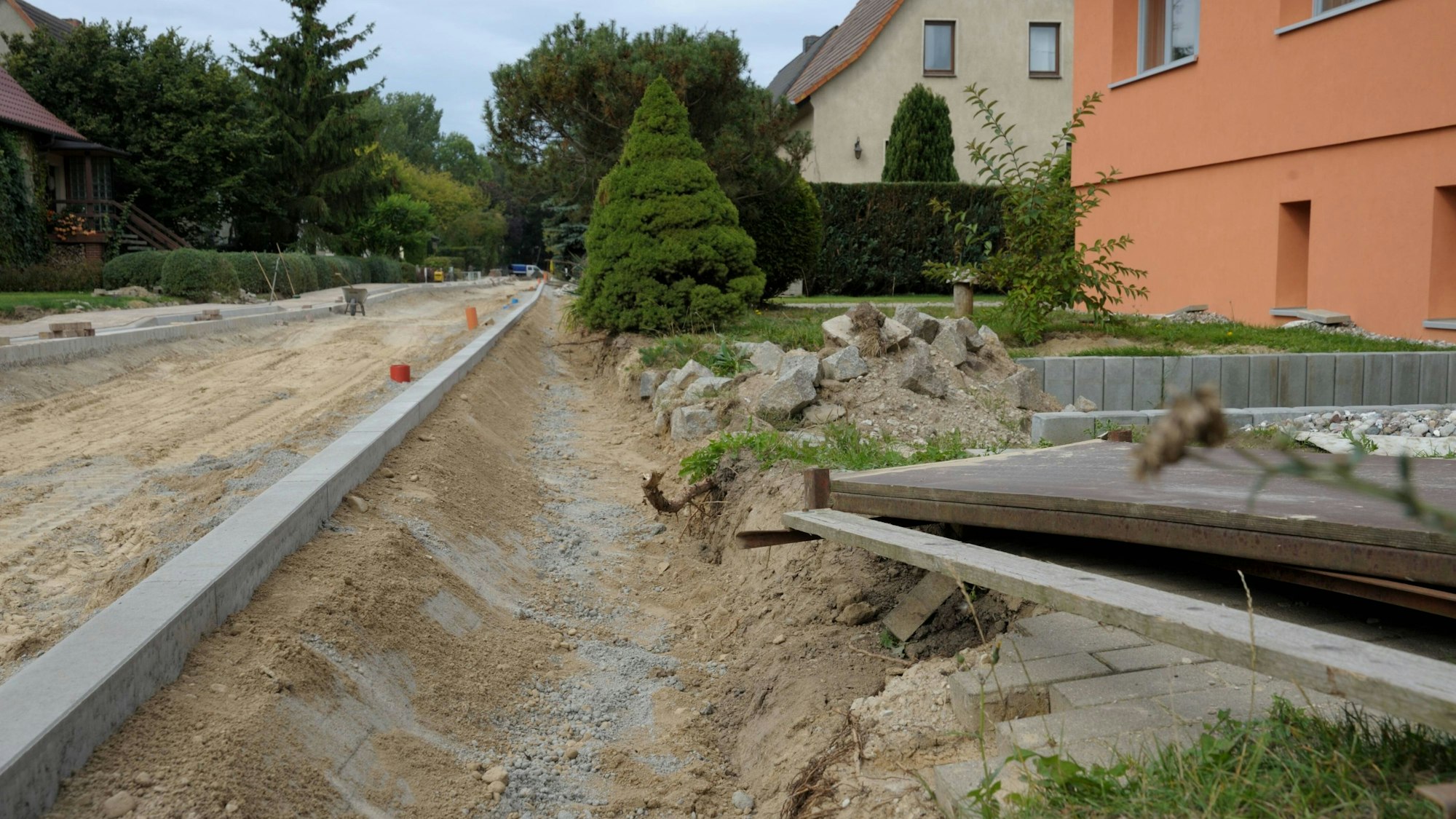 Baustelle Straße mit Sand, Graben und neuen Bordsteinen