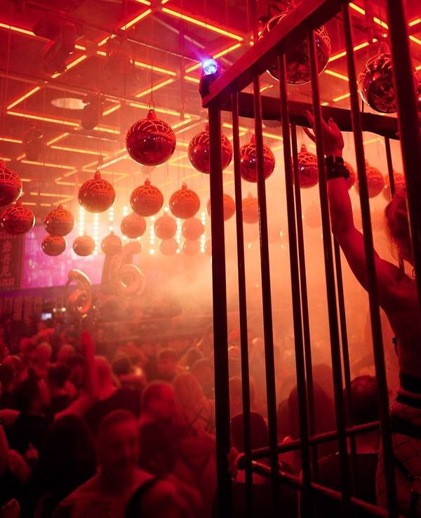 Leicht bekleidete Menschen tanzen im Scheinwerferlicht in einer Disco.