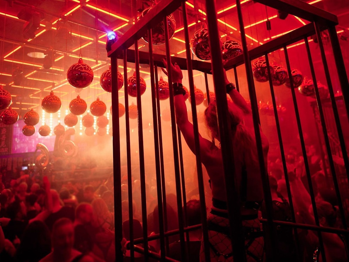 Leicht bekleidete Menschen tanzen im Scheinwerferlicht in einer Disco.