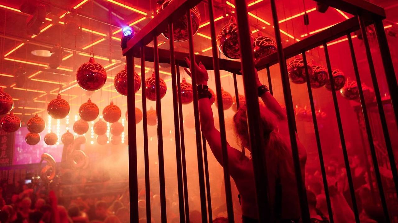 Leicht bekleidete Menschen tanzen im Scheinwerferlicht in einer Disco.