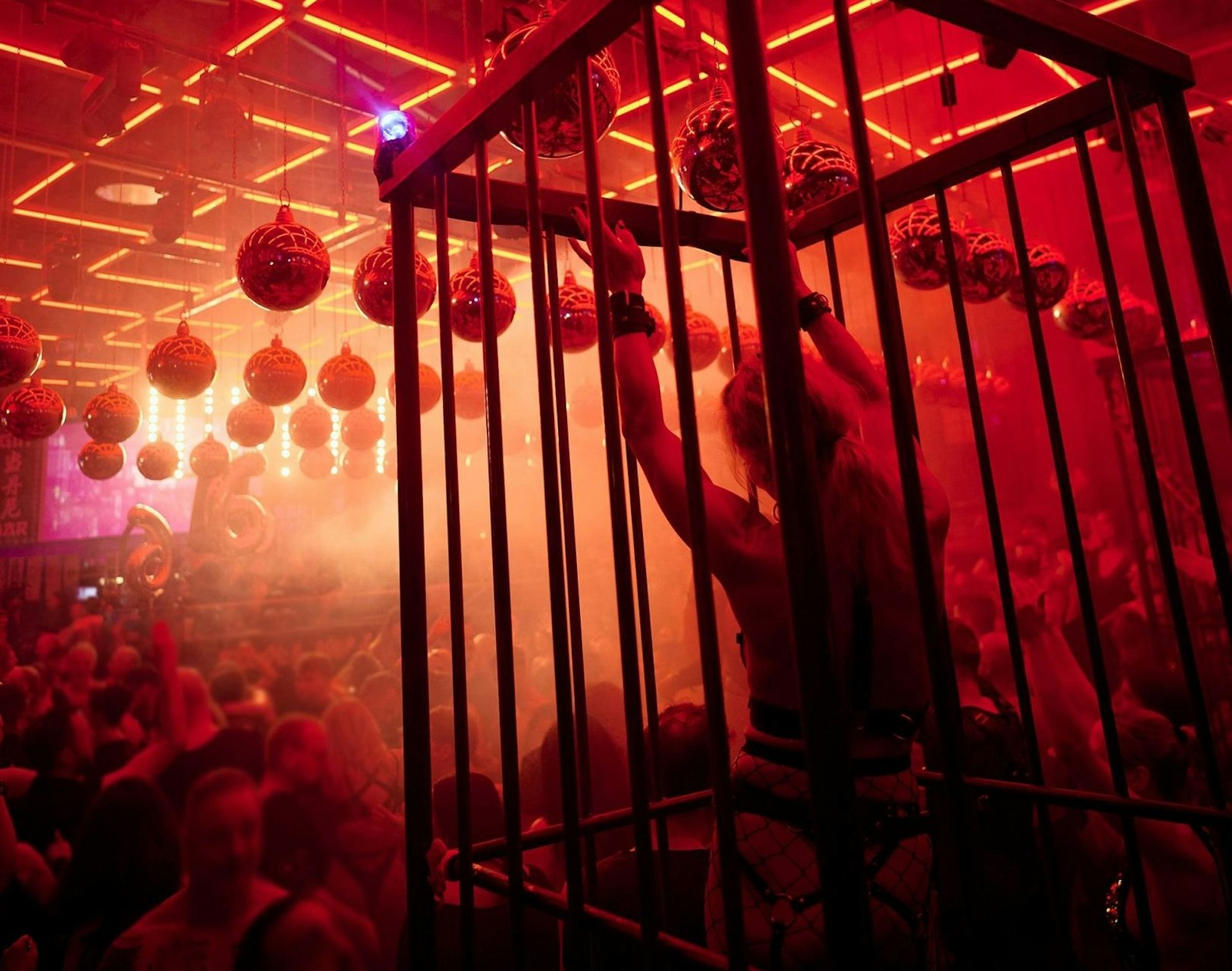 Leicht bekleidete Menschen tanzen im Scheinwerferlicht in einer Disco.