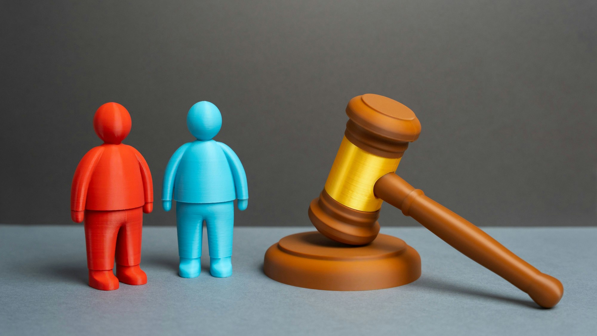 Gerichtssaal symbolisch mit Figuren und Richterhammer