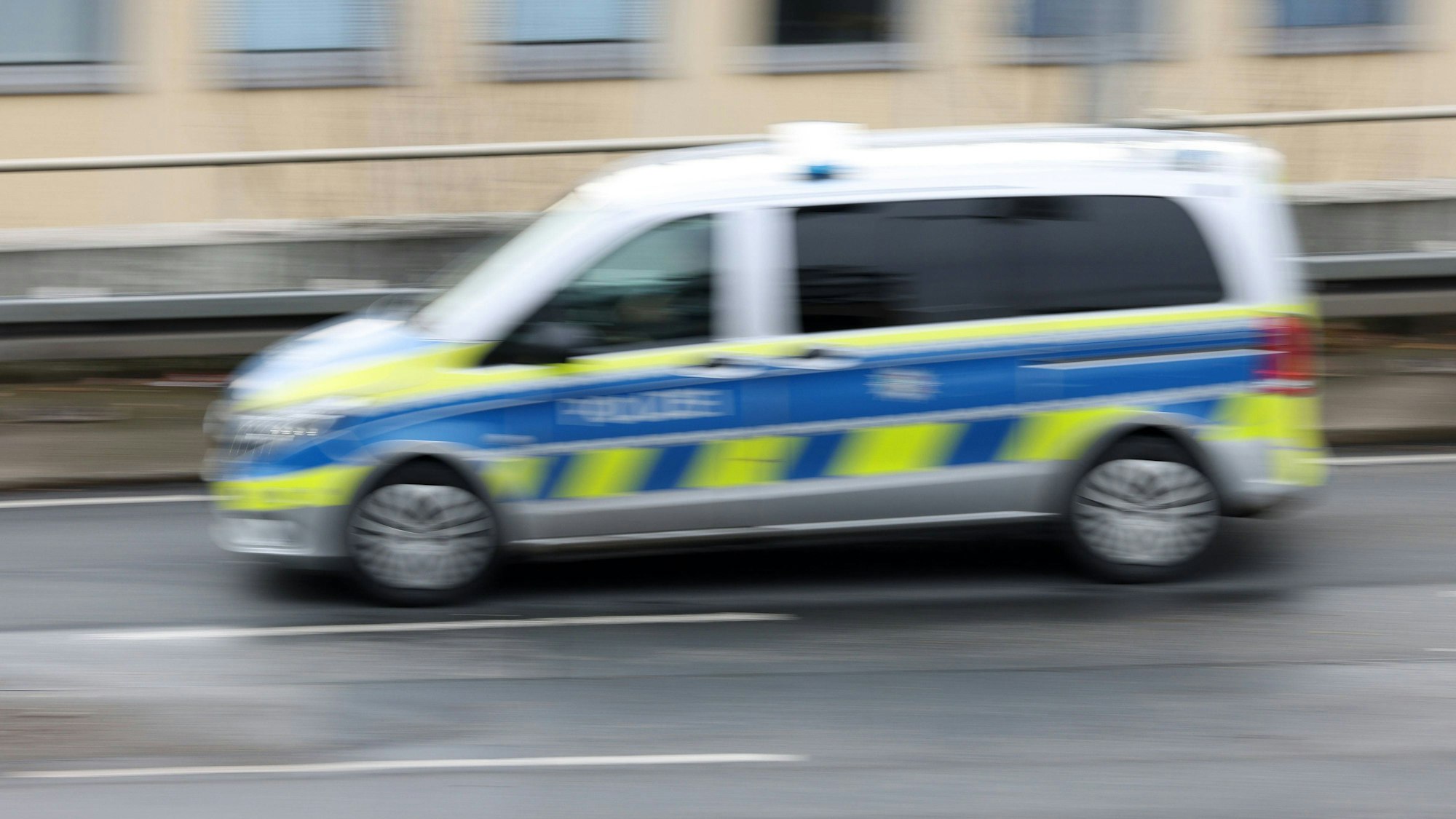 Deutsches Polizeiauto fährt mit Bewegungsunschärfe durch Siegen auf einer Straße