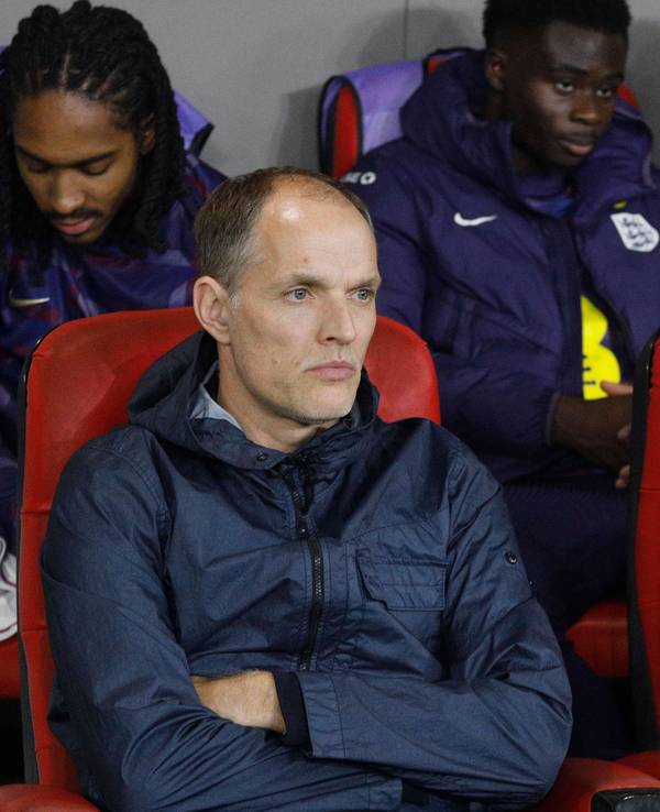 Thomas Tuchel sitzt mit verschränkten Armen auf der Ersatzbank.