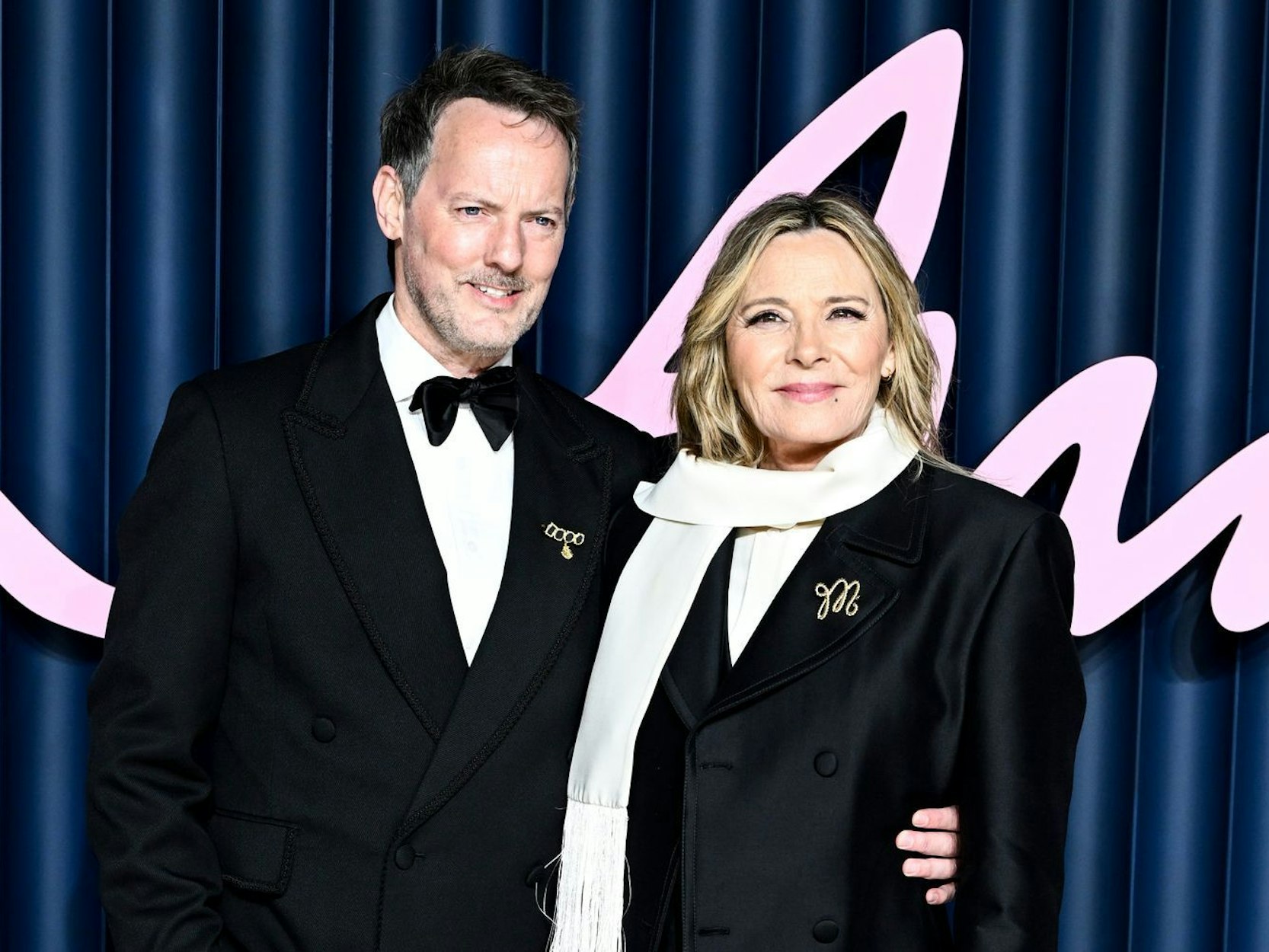 Ein Paar posiert, dabei hat der Mann den Arm um die Frau gelegt.