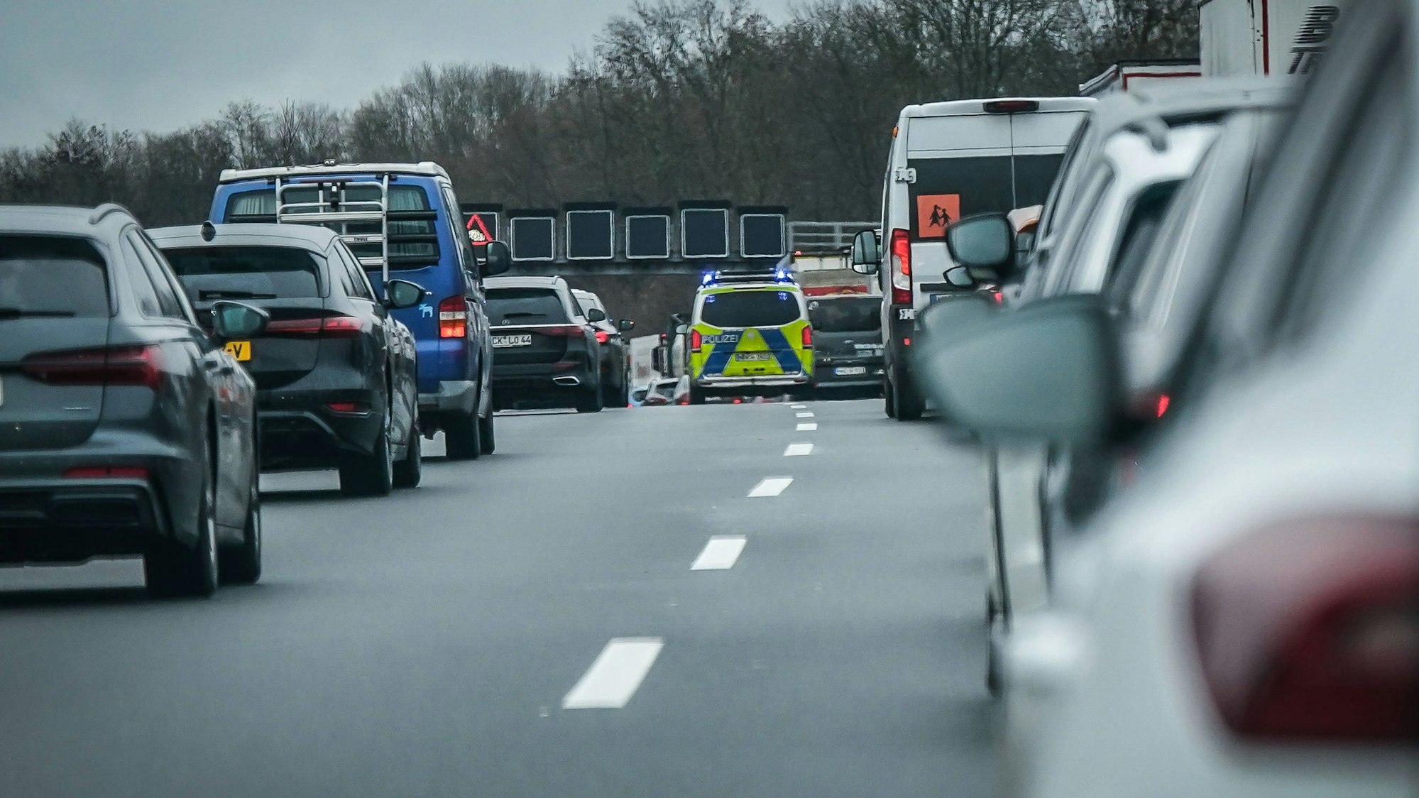 Stau auf deutscher Autobahn mit Polizeifahrzeug, Blaulicht und Rettungsgasse bei Winterwetter