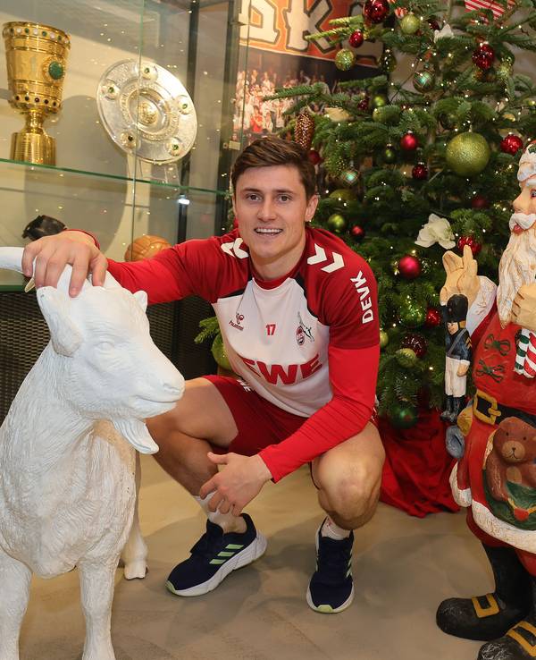 Alessio Castro-Montes hockt vor einem Weihnachtsbaum und neben einer Weihnachtsmann-Figur und streichelt einem weißen Geißbock aus Gips über den Kopf.