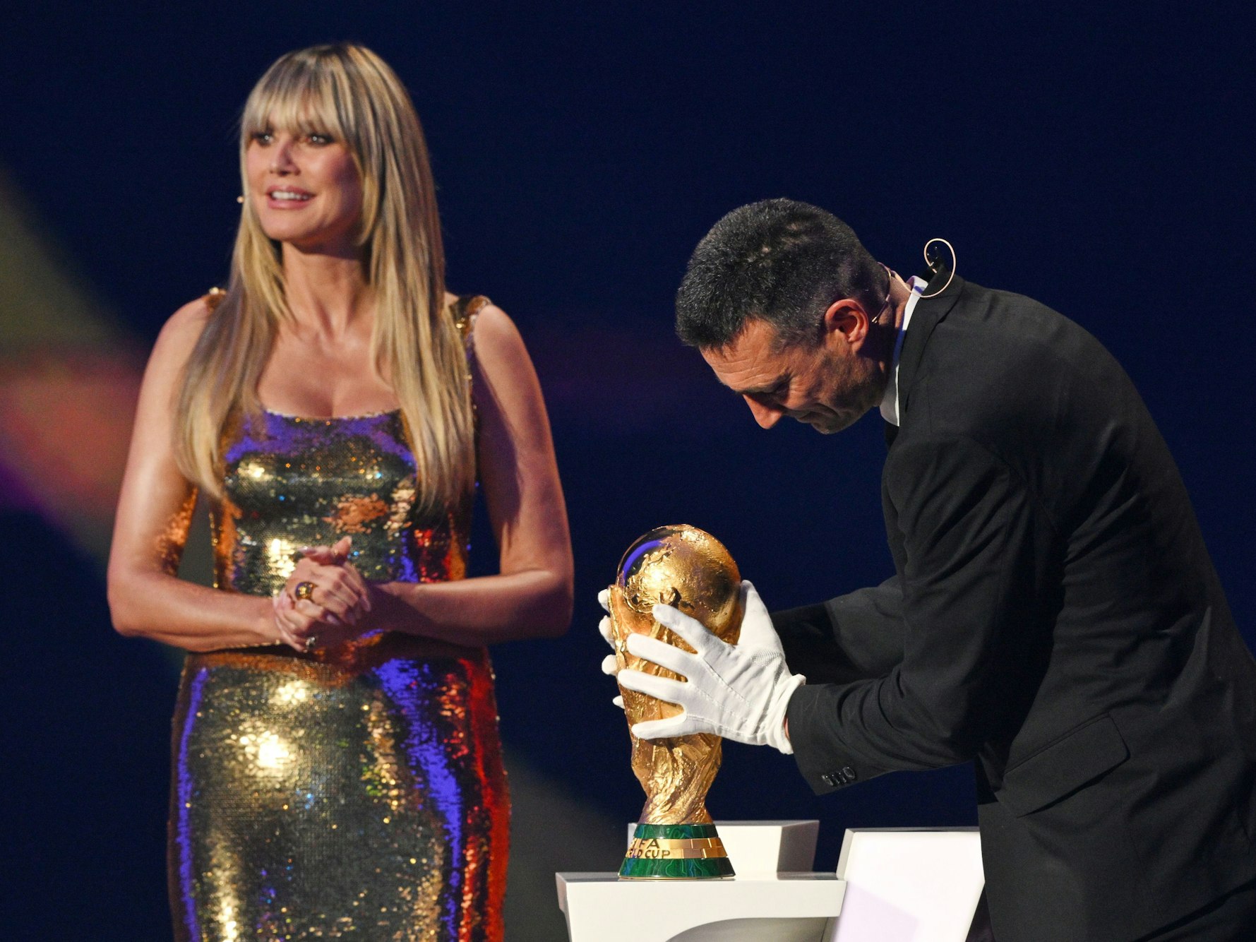 Moderatorin Heidi Klum sieht zu, wie der argentinische Trainer Lionel Scaloni die WM-Trophäe für die Auslosung aufstellt. ZDF-Zuschauer und Zuschauerinnen sahen derweil die heute-Nachrichten.