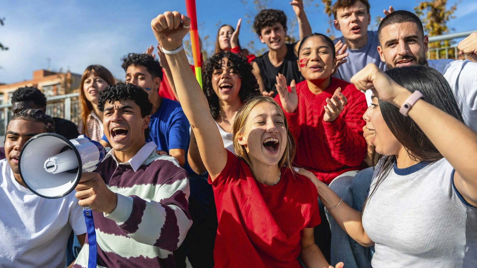 Gruppe junger Aktivisten bei einer Tagesdemonstration, die Fäuste heben und begeistert schreien