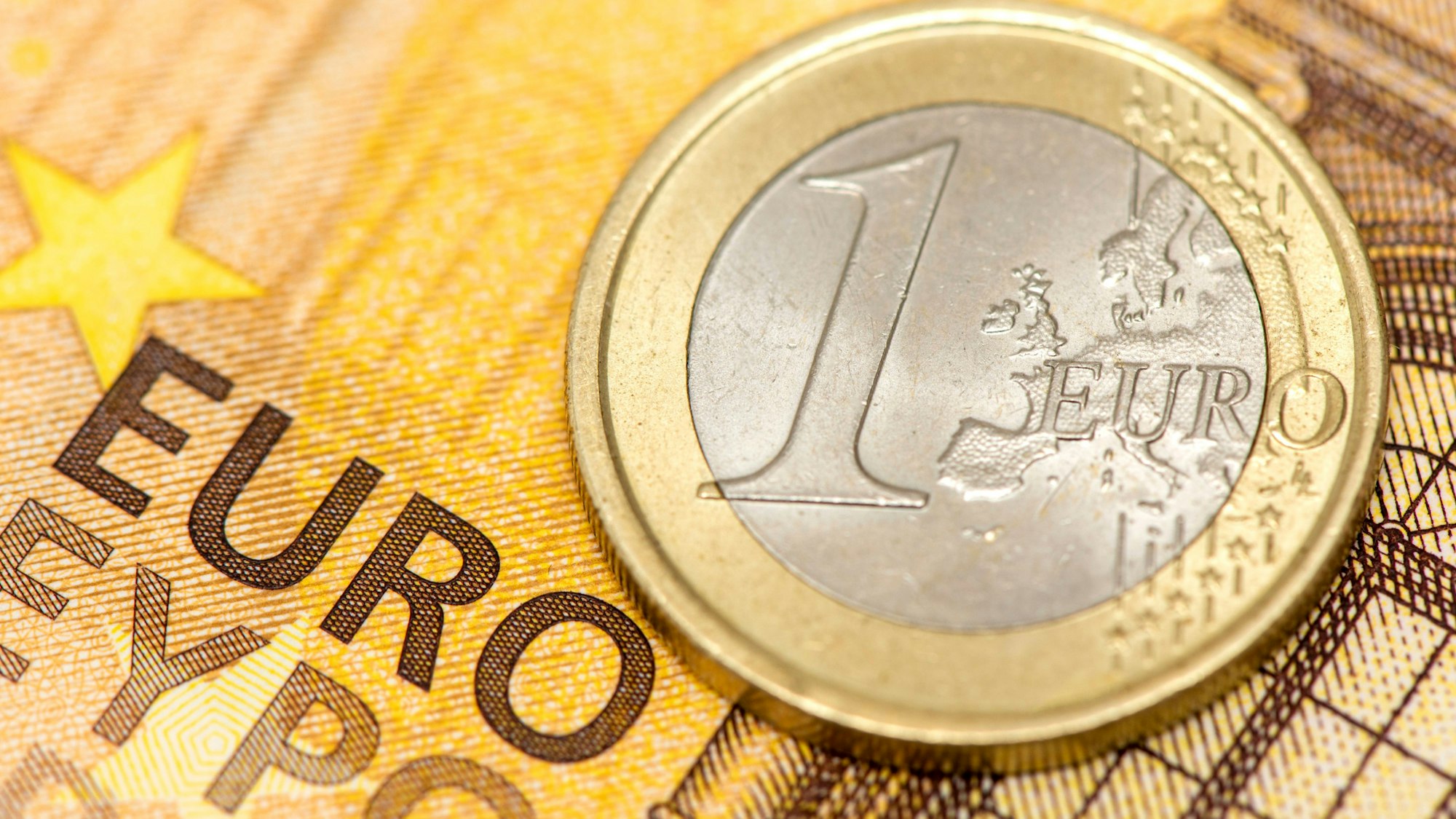 Eine 1-Euro-Münze liegt auf einem gelben Euro-Geldschein mit dem Schriftzug 'EURO'