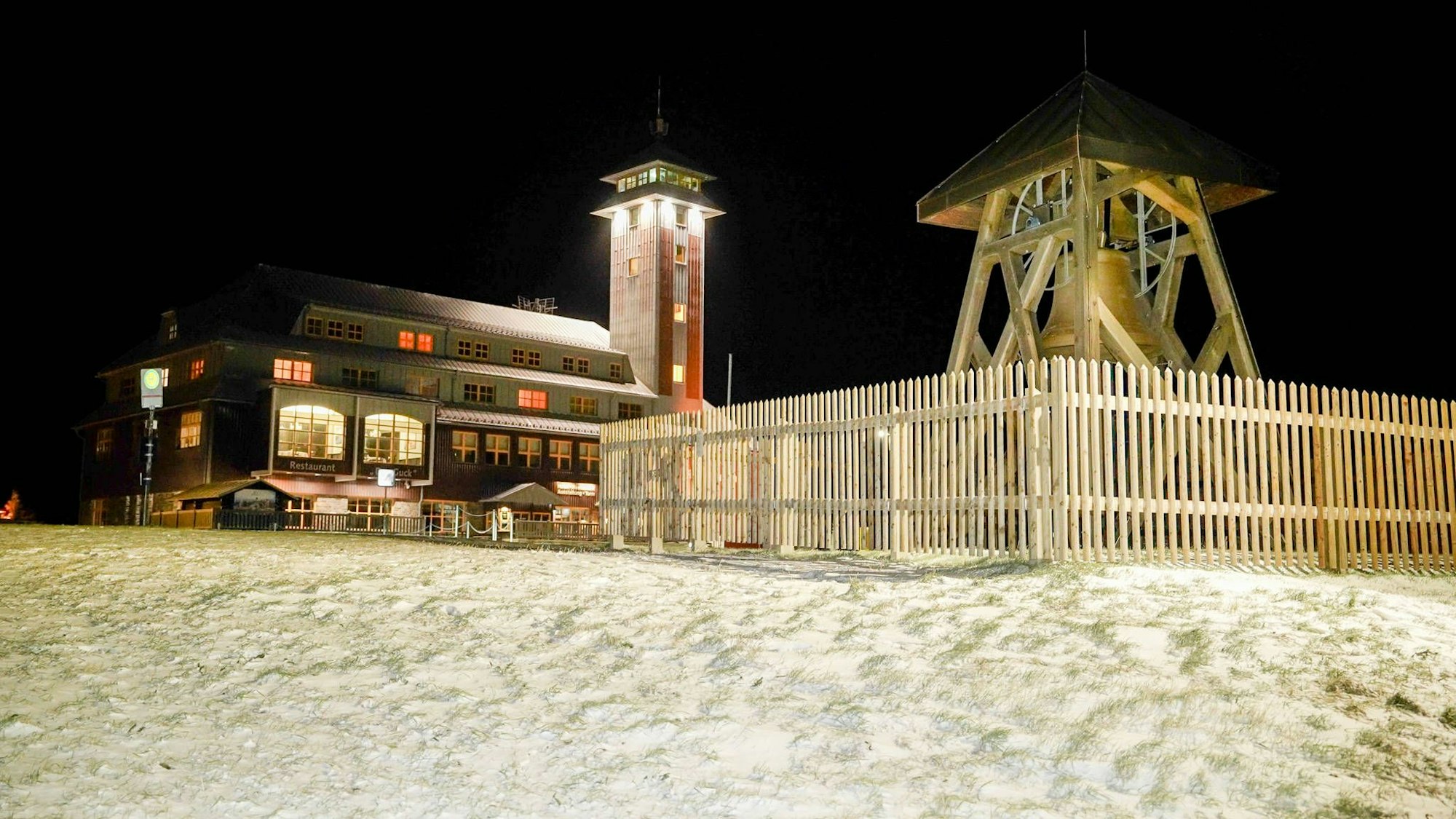 Nachtaufnahme des Fichtelbergs im tiefen Winter mit beleuchteten Gebäuden und Glockenturm