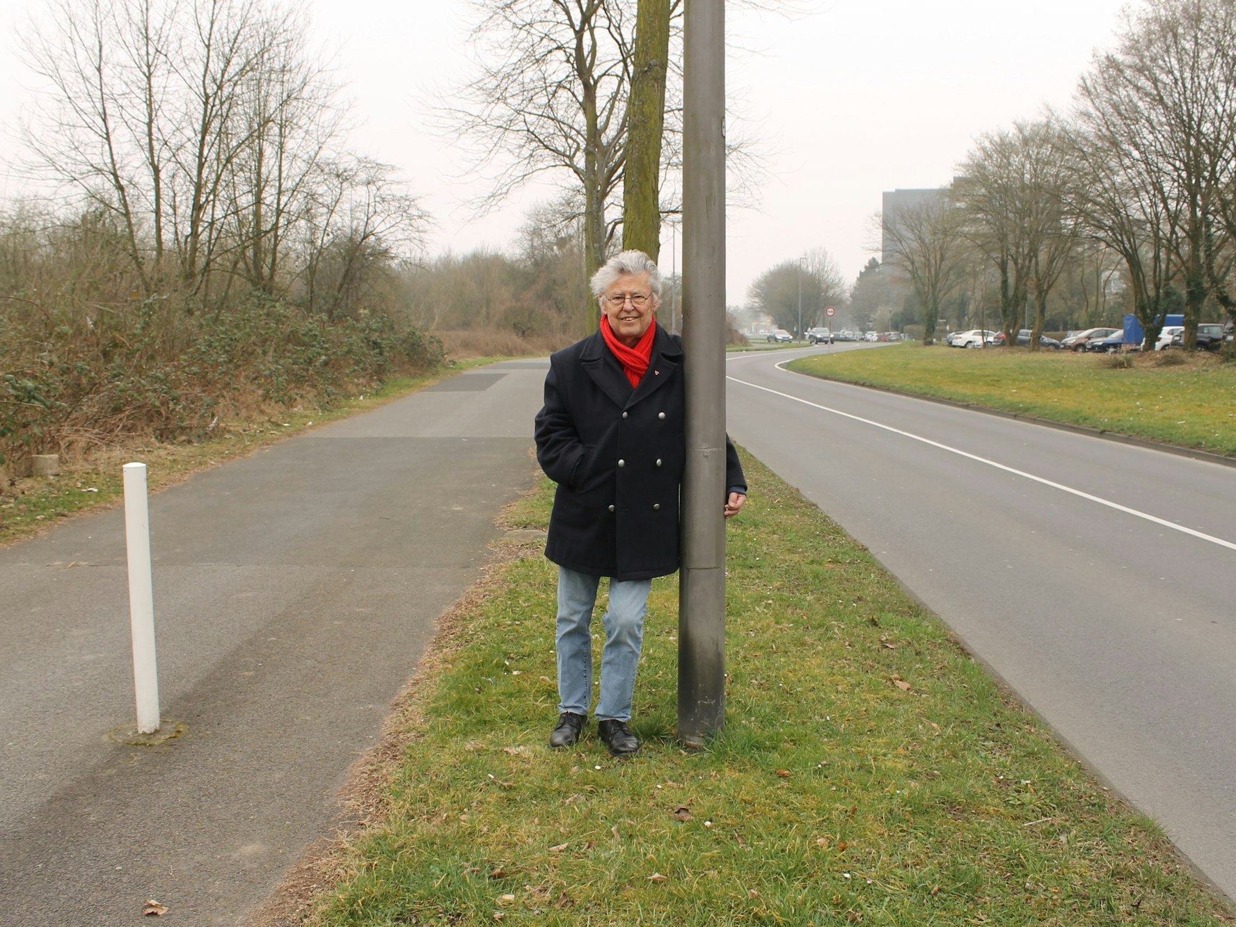 Ein Mann lehnt an einem Laternenmast in Köln.