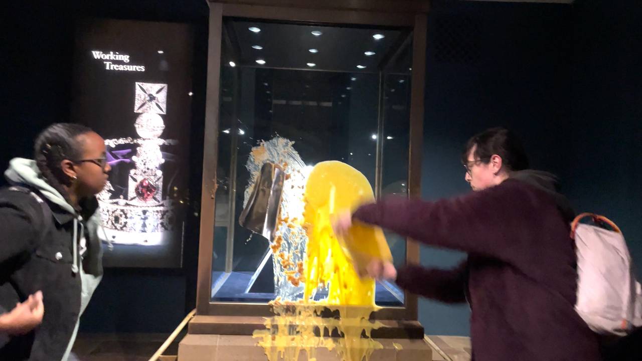 Handout aus einem von Take Back Power herausgegebenen Video, das zwei Unterstützerinnen von Take Back Power zeigt, die einen Nachtisch, mutmaßlich Apfel-Crumble und Vanillesoße, über die Kronjuwelen im Tower of London werfen. Der Tower of London ist nach dem Anschlag auf die Kronjuwelen bis auf weiteres geschlossen worden. Vier Menschen seien festgenommen worden, teilte die Polizei mit.